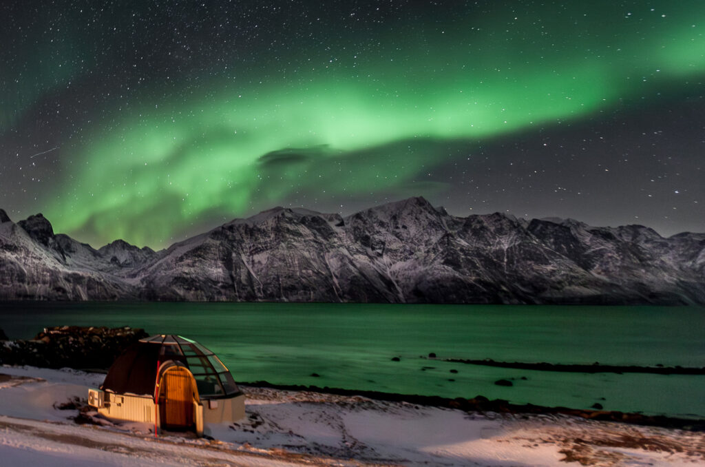 northern lights over glass igloo in Norway